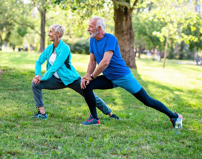 elderly couple stretching outside